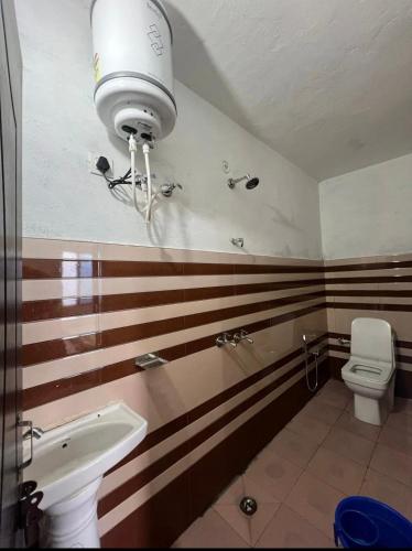 baño con lavabo y aseo con rayas en mayur homestay, en Ukhimath
