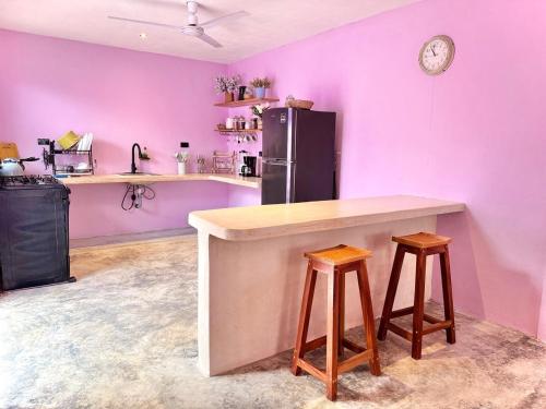 a kitchen with purple walls and a counter and stools at Casa Lina in Valladolid