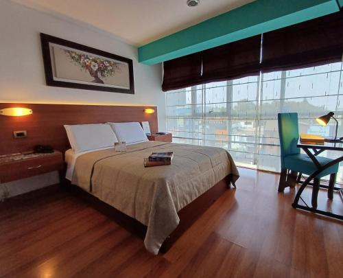 a bedroom with a bed and a desk and a window at Hotel Vila Santa in Lima