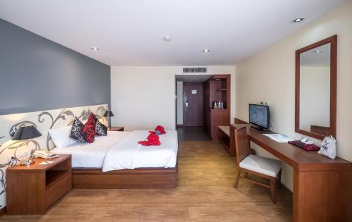 a bedroom with a bed and a desk and a mirror at Grand Jomtien Palace Hotel - SHA Extra Plus in Jomtien Beach