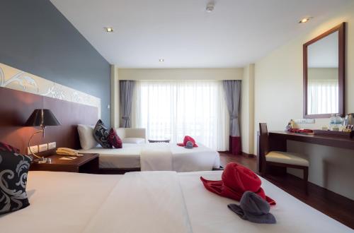 a hotel room with two beds and a mirror at Grand Jomtien Palace Hotel - SHA Extra Plus in Jomtien Beach