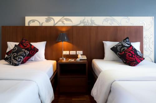 a hotel room with two beds and a table with a lamp at Grand Jomtien Palace Hotel - SHA Extra Plus in Jomtien Beach