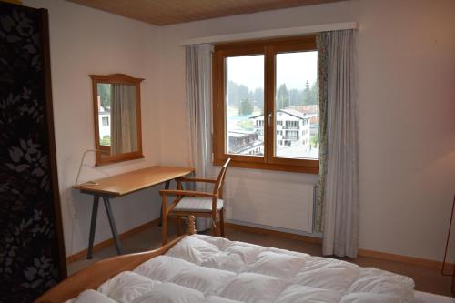 a bedroom with a bed and a desk and a window at Rhodania A 3004 Sr in Lenzerheide