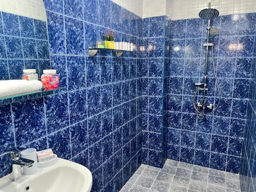 a blue tiled bathroom with a shower and a sink at Къща за гости Шарон in Petrich