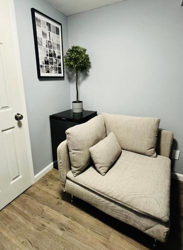 a couch in a living room with a plant on a table at Cozy Apartments close to New York City in North Bergen