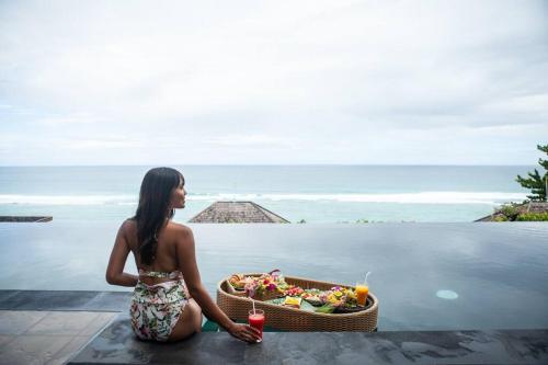 a woman sitting in the water with a basket of food at Nusa dua Ocean View with Private Beach in Nusa Dua