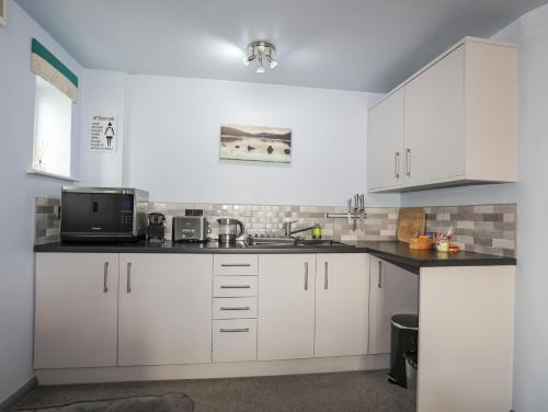 a white kitchen with white cabinets and a microwave at Tegid Lakeside - Bala Lake in Bala