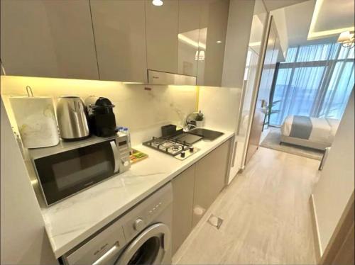 a small kitchen with a stove and a microwave at Dubai Galaxy in Azizi Riviera Luxury Studio in Dubai