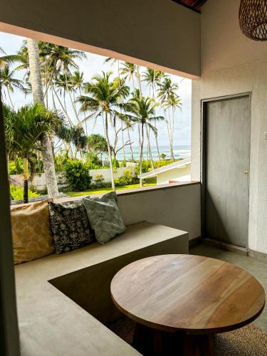 a room with a table and a couch and palm trees at Surf Lodge Madiha in Matara