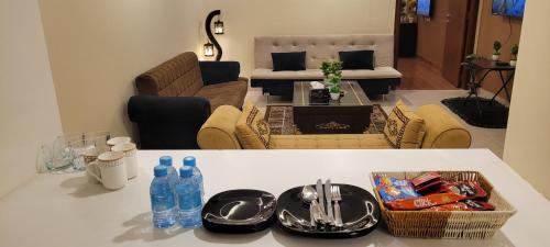a living room with a table with plates and water bottles at Goldcrest Apartments in Lahore