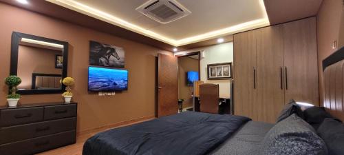 a bedroom with a large bed and a tv at Goldcrest Apartments in Lahore