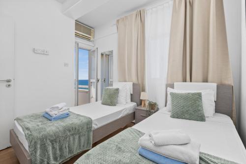 two beds in a room with a window at Lazuli Sea View Beachfront- Ap 61 in Larnaca