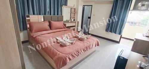 a bedroom with a pink bed with flowers on it at Nontharat Mansion in Nonthaburi