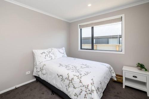 a white bedroom with a bed and a window at Stonehenge Retreat in Martinborough
