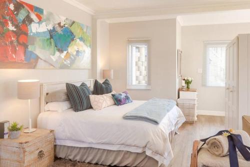 a white bedroom with a large bed with pillows at SandDollar - Self Catering Seaside Getaway in Cape St Francis