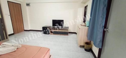 a room with a bed and a tv in a room at Nontharat Mansion in Nonthaburi