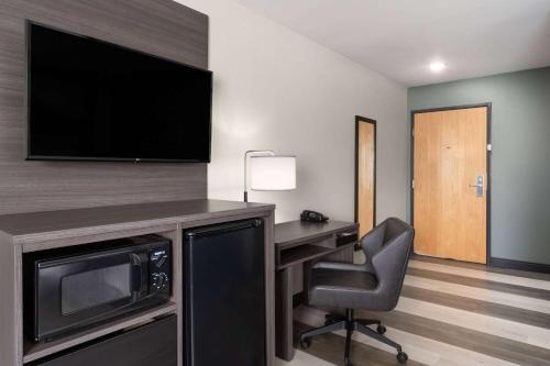 a hotel room with a desk with a microwave and a television at Super 8 by Wyndham Big Timber in Big Timber