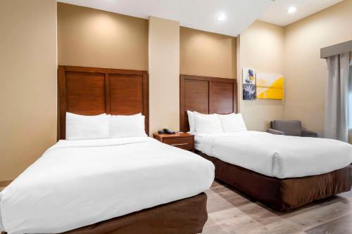 two beds in a hotel room with white sheets at Comfort Suites Monaca in Monaca