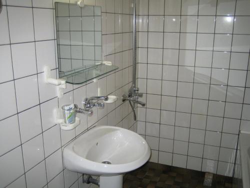 un bagno piastrellato bianco con lavandino e specchio di Arbanassi Hotel a Arbanasi