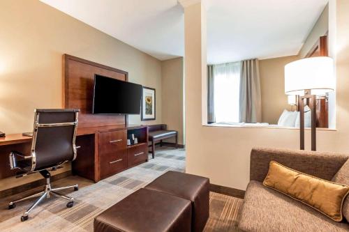 a hotel room with a desk and a chair and a television at Comfort Suites University Brookings in Brookings