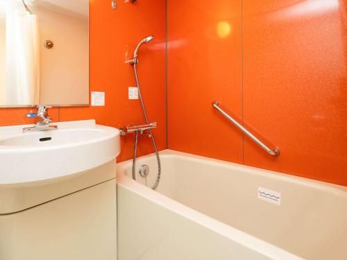 an orange bathroom with a sink and a shower at Comfort Inn Zentsuji Inter in Marugame