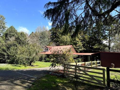 a house with a fence in front of it at Kauri Lodge in Taupaki