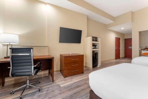 a hotel room with a desk and a bed and a tv at Comfort Suites Monaca in Monaca