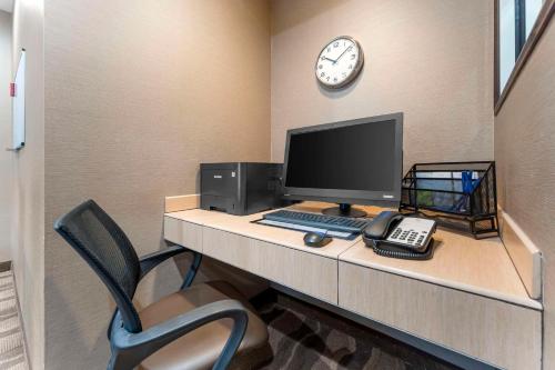 a desk with a computer and a clock on a wall at Comfort Suites Monaca in Monaca