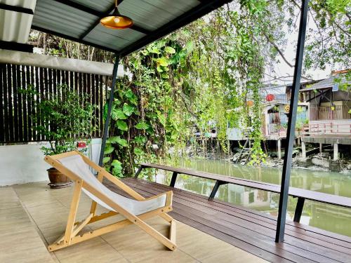 a wooden chair sitting on a deck with a table at Kirin Riverside Homestay with AC, WiFi in Bangkok in Rat Burana
