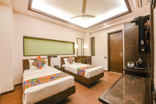 a hotel room with two beds and a large screen at FabHotel Aashraye in New Delhi
