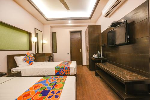 a room with two beds and a flat screen tv at FabHotel Aashraye in New Delhi