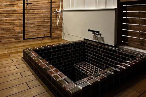 a large black tiled bath tub in a bathroom at ZABOCON YOICHI Villa in Yoichi