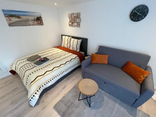 a bedroom with a bed and a couch and a clock at 'StudioCDG fr' Jardin, Studio proche near CDG Roissy airport, Parc Expositions, Stade de France, Arena, Disney, Asterix in Villepinte