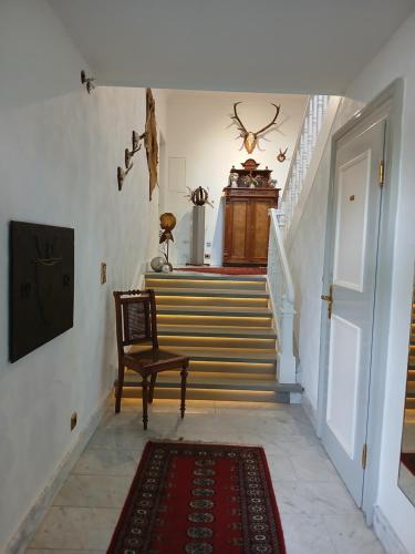 a hallway with stairs with a chair and a door at Ferienwohnung im alten Forstamt in Erndtebrück