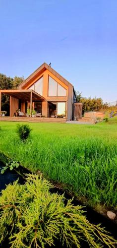 a house in a field with green grass at Stodoła Rzym - domek, jacuzzi, sauna, jezioro, las in Kożyczkowo