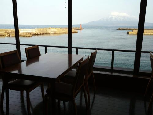 a table and chairs with a view of the ocean at REBUN Hotel SARYO in Kafuka