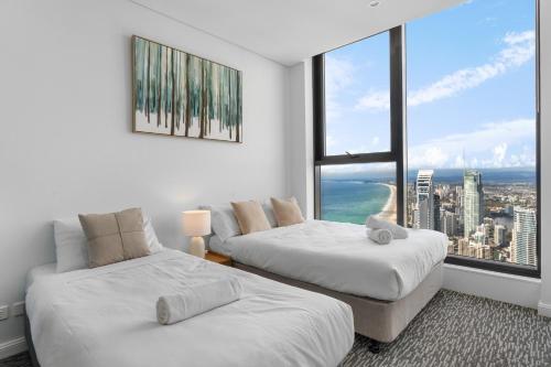 two beds in a room with a view of the city at The Ocean - Beachfront 72F 3Bedroom Skyhome Ocean Views with Parking & Resort Facilities in Gold Coast