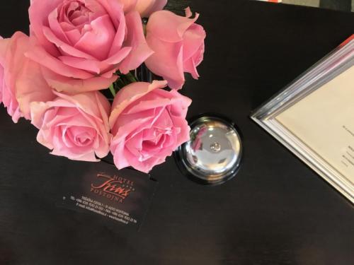 a vase filled with pink roses next to a certificate at Hotel Kras in Postojna