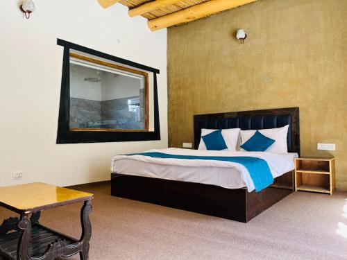 a bedroom with a bed with a mirror and a table at Hunder Tamarix Resort in Hundar