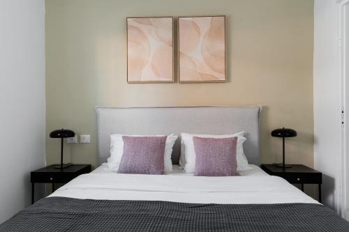 a bedroom with a white bed with two purple pillows at Blueground Florentine, City view in Tel Aviv