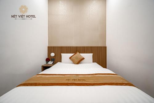 a bedroom with a white bed with a wooden headboard at Nét Việt Hotel Vincom Sóc Trăng in Soc Trang