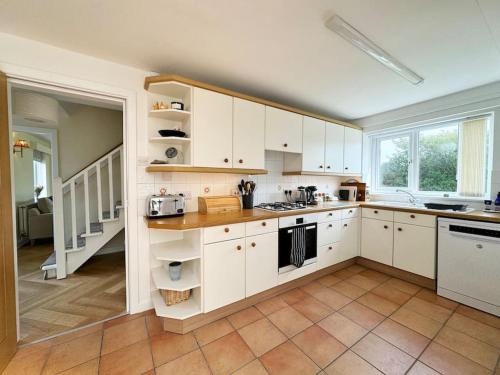 a kitchen with white cabinets and a large window at Beach Access-Ynys Cartref-4-Bed in Trearddur
