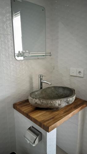 a bathroom with a stone sink and a mirror at Sujiwa Ubud Hotel & Villa in Ubud