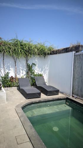 a swimming pool with two lounge chairs next to it at Sujiwa Ubud Hotel & Villa in Ubud