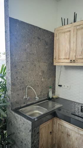 a kitchen with a sink and wooden cabinets at Sujiwa Ubud Hotel & Villa in Ubud