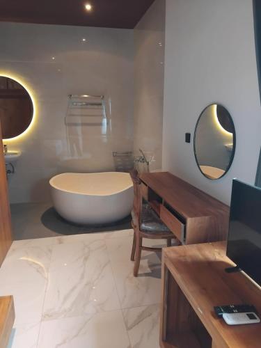 a bathroom with a tub and a sink and a mirror at Sujiwa Ubud Hotel & Villa in Ubud