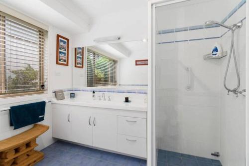 Un baño blanco con ducha y lavabo. en Home, but closer to the beach, en Sunshine Bay