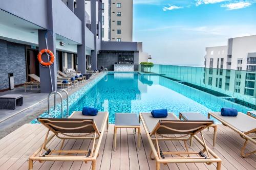 a pool on the roof of a building with lounge chairs at Jazz Service Suites Penang in George Town