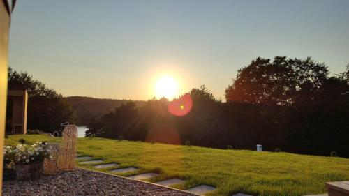 a sunset over a field with the sun setting at Stodoła Rzym - domek, jacuzzi, sauna, jezioro, las in Kożyczkowo
