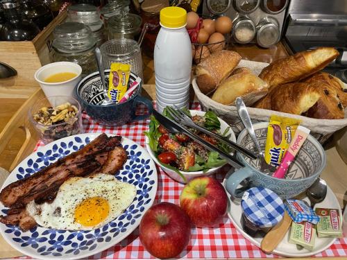 a table with a plate of breakfast food with eggs and bread at La Clé des Champs - Studio PiscineSPA-Sauna au jardin tropical idyllique et bucolique in Jouarre